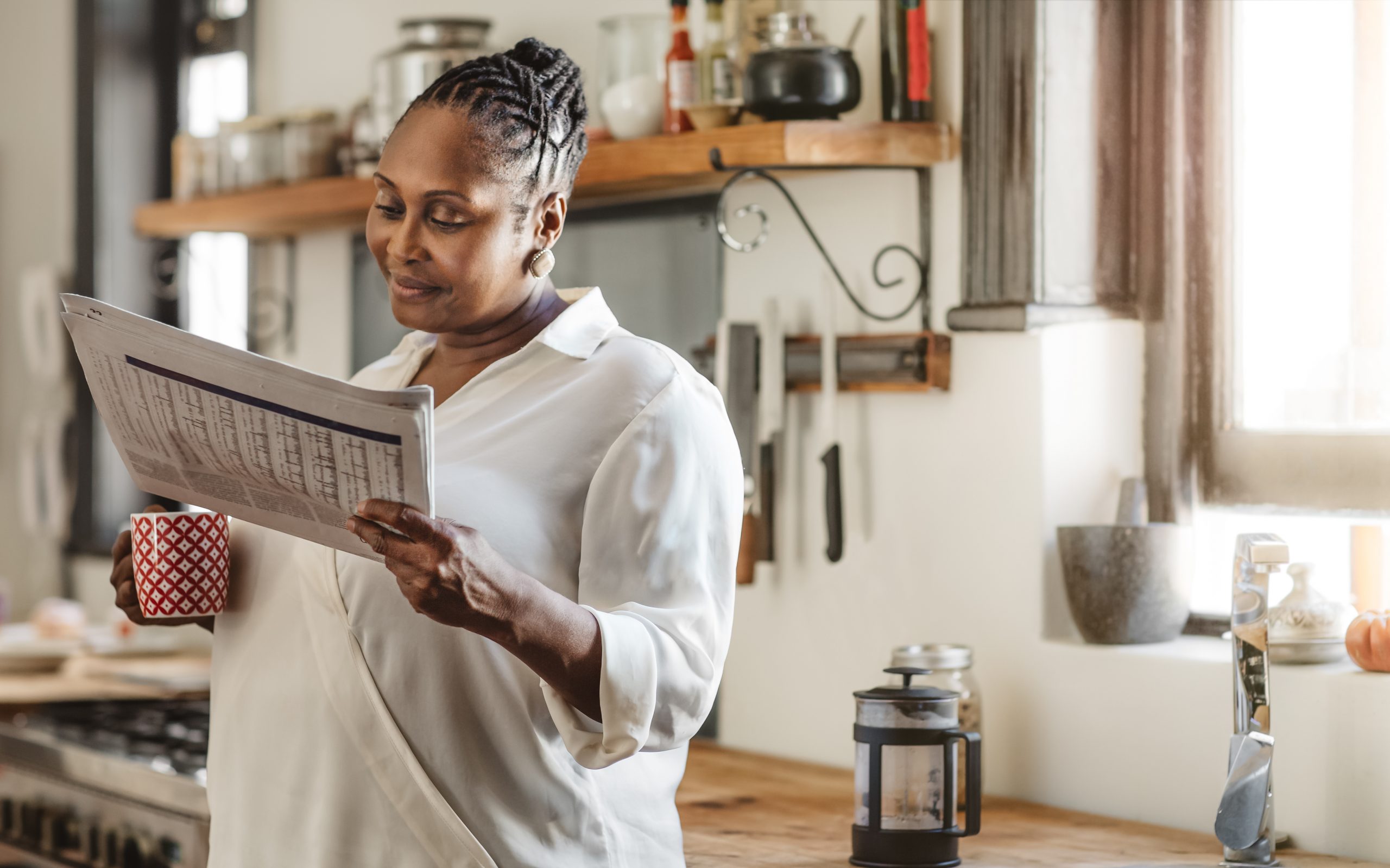 Smiling African American woman reading the newspaper in the morning